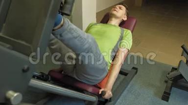 一个超重的男人在健身房里用模拟机做腿部<strong>按压</strong>。健身训练。健康生活方式理念